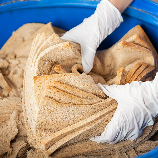 Eine Hand greift in eine Schüssel mit Brot.